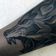 a man's arm with a black and grey wolf tattoo on the left forearm