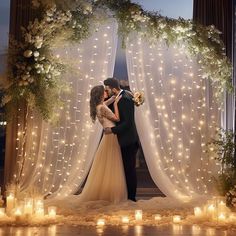 a bride and groom kissing in front of a wedding arch with lit candles on the floor