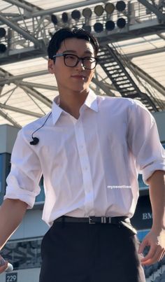 a young man wearing glasses and a white shirt is standing in front of a stage