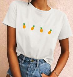 a woman wearing a white shirt with pineapples on it