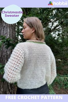 a woman standing in front of a tree wearing a white sweater with crochet