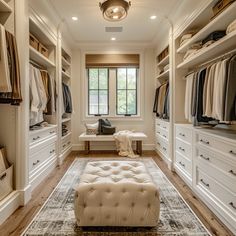 a large walk in closet with lots of white furniture and drawers on either side of the room