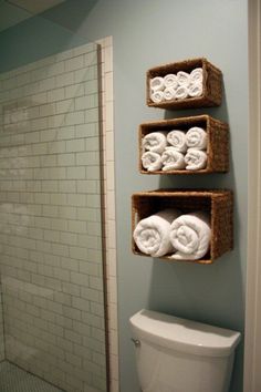 three baskets are hanging on the wall above a toilet