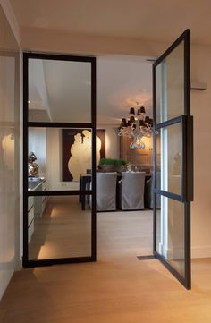 an open door leading to a kitchen and dining room with chandelier hanging from the ceiling