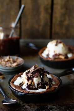 three skillets filled with ice cream, chocolate and nuts on top of a table