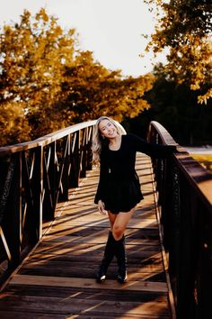 a woman is standing on a bridge posing for the camera with her legs spread out