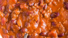 a spoon in a bowl filled with chili and beans