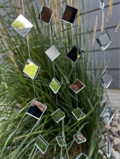 a wind chime hanging in front of a plant with lots of mirrors on it