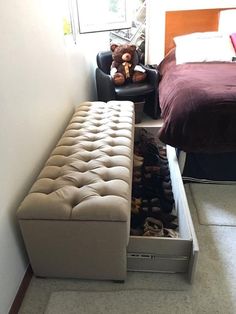 a bedroom with a bed, chair and footstool that has shoes in it