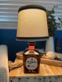 a bottle lamp sitting on top of a wooden table next to a tray with logs