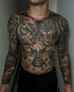 a man with tattoos on his chest is standing in front of a mirror and looking at the camera