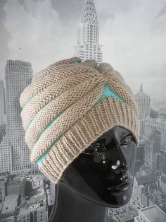 a mannequin head wearing a knitted hat in front of a cityscape