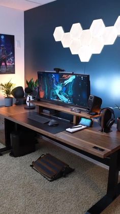 a computer desk with a large monitor and keyboard on it in front of a blue wall