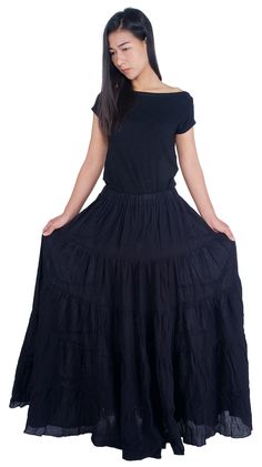 a woman is wearing a black dress and standing in front of a white background with her hands on her hips