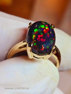 Very bright black opal 10x14mm 5.24cts. nice consistent  galaxy pattern mounted on a simple solitaire solid 14k gold ring, I like the simplicity and solidness of this ring,its heavy for it's size.  Hard to photograph the stone because it is so bright, looks even better in person. I will tighten the prongs when the ring size is determined. Multicolor Opal Round Ring, Black Opal Cabochon Ring As Gift, Black Opal Ring With Cabochon As A Gift, Black Oval Cabochon Opal Ring, Black Cabochon Opal Ring, Multicolor Opal Ring, Black Opal Jewelry, Black Fire Opal, Galaxy Pattern