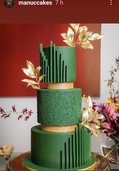 a three tiered green cake with gold leaves on top