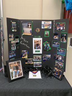 a black table topped with pictures and framed photos next to a blue ribbon covered wall