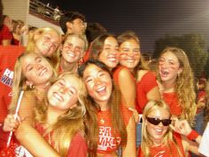 a group of young women standing next to each other in front of a soccer field