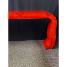 a red bench sitting on top of a carpeted floor next to a black wall