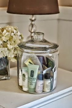 a glass jar with some skin care products in it and a lamp next to it