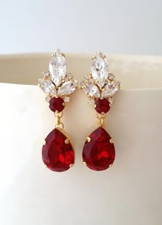 two pairs of red and white earrings with crystal stones on top of each earring