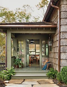 the front door of a house with potted plants on the porch and steps leading up to it