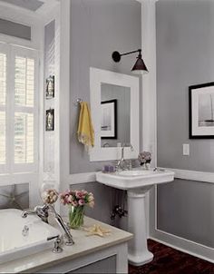 a white bathtub sitting next to a sink under a window with shutters on it