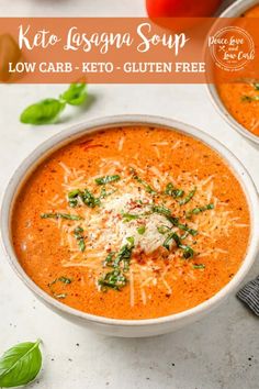 two bowls of tomato soup with parmesan cheese on top and basil sprigs