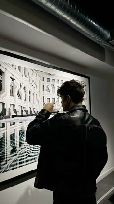 a man standing in front of a painting on the wall with his hands to his face