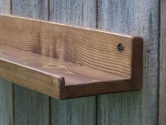 a wooden shelf mounted to the side of a fence