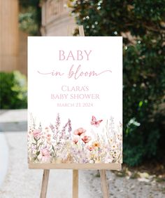 a baby in bloom sign is shown on an easel with pink and white flowers