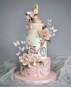 a three tiered cake decorated with flowers and a bunny on top