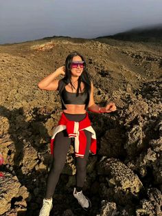 a woman is sitting on some rocks wearing sunglasses