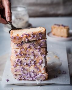 someone is cutting into a cake with purple sprinkles on it and holding a fork