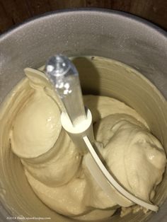 a mixing bowl filled with cream and a plastic spoon