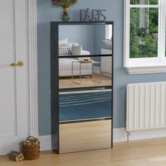 a mirror reflecting the inside of a room with blue walls and wood flooring in front of a white radiator