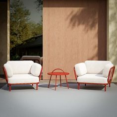 two chairs and a table sitting in front of a wooden door on a concrete floor