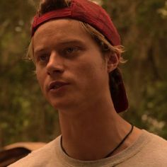 a young man with a red bandana on his head looking at something in the distance