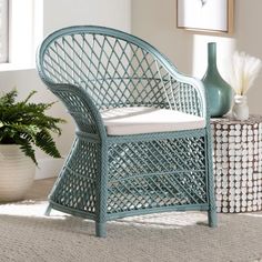 a blue wicker chair sitting on top of a rug next to a potted plant