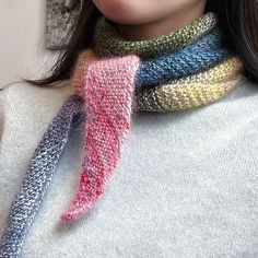 a woman wearing a multicolored knitted neck scarf with a pink, blue, yellow and green tie