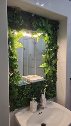 a bathroom sink with a mirror and plants on the wall