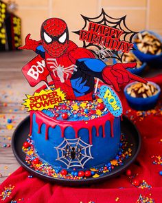 a spiderman birthday cake with sprinkles and decorations