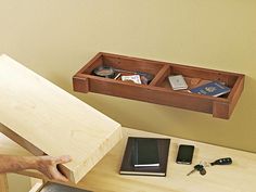 a wooden desk topped with a laptop computer next to a shelf filled with books and other items