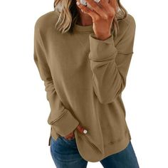 a woman taking a selfie while wearing a brown sweatshirt and jeans with her phone in her hand