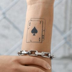 a person with a tattoo on their arm holding onto a chain and wearing a bracelet