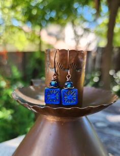 The centerpiece for these stunning boho earrings is a cobalt blue tile bead with a gorgeous starburst.  Another petite pair of earrings! Simply gorgeous Czech glass! Love the look! These unique beauties are just under two inches in length, including the copper hooks.  The Czech glass square bead is accented with a complimentary Rondelle bead and wavy copper disc.  These square starburst beads are some of my favorite beads because of the richness of the color and the design.  One of a kind. Lightweight! Petite. Handmade. Smoke free artist studio. Artisan Blue Earrings For Festival, Artisan Blue Earrings, Artisan Blue Drop Earrings, Blue Earrings With Ear Wire For Festival, Nickel-free Blue Earrings For Festival, Blue Drop Earrings For Festival, Artisan Blue Nickel-free Earrings, Adjustable Blue Earrings For Festival, Bohemian Blue Nickel-free Earrings