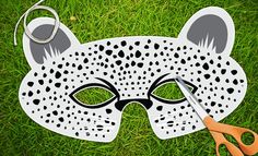 a white mask with black dots on it sitting in the grass next to some scissors