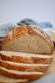 a loaf of bread sitting on top of a cutting board next to slices of bread