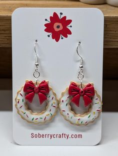 a pair of cookie earrings with a red bow on it's earwires