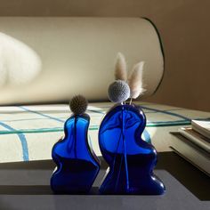 two blue glass vases sitting on top of a table next to a stack of books